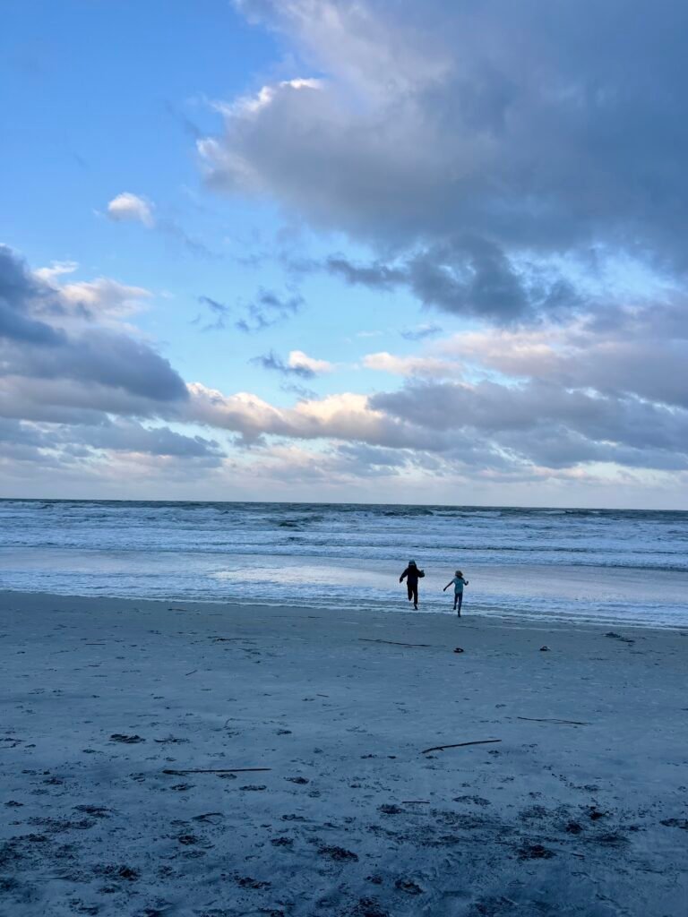 two children playing on the beach at sunset